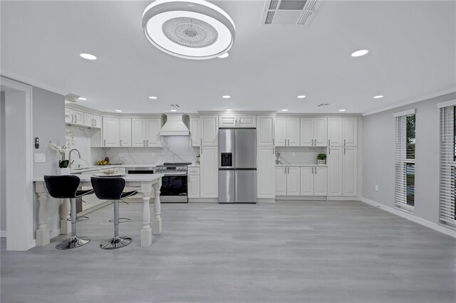 9334 Ledgestone Ln, Port Richey, FL 34668 - kitchen featuring visible vents, custom exhaust hood, appliances with stainless steel finishes, light countertops, and a breakfast bar area