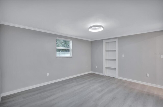 9334 Ledgestone Ln, Port Richey, FL 34668 - empty room with ornamental molding, built in features, baseboards, and wood finished floors