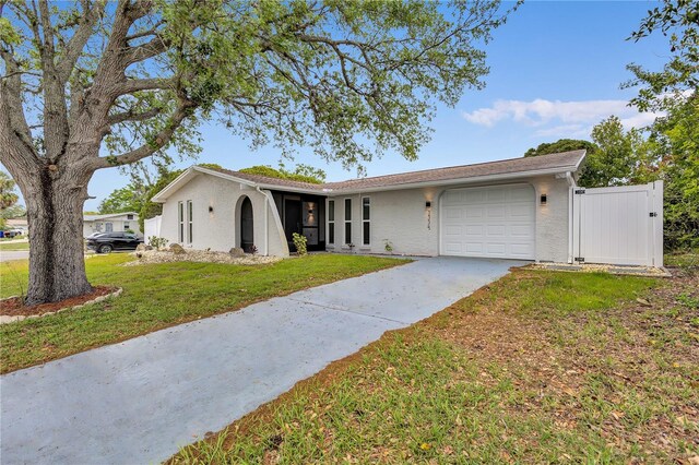 9334 Ledgestone Ln, Port Richey, FL 34668 - ranch-style house featuring stucco siding, driveway, a front yard, a garage, and a gate