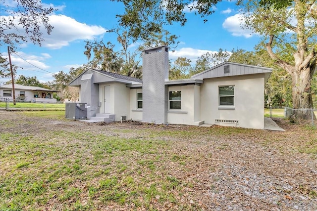 back of property featuring central air condition unit and a lawn