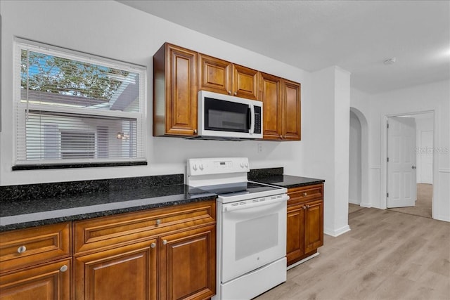 kitchen with white electric range, dark stone counters, and light hardwood / wood-style flooring