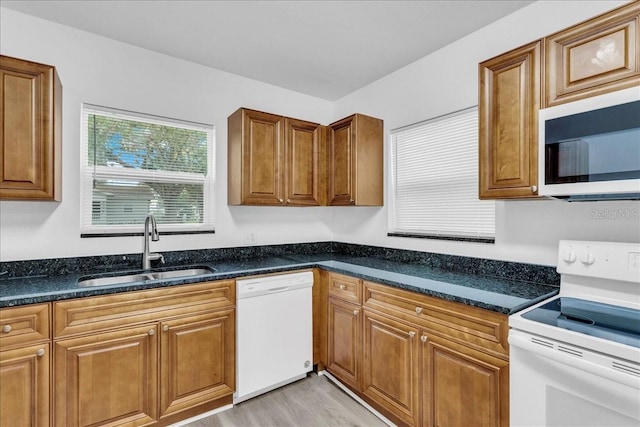 kitchen featuring light hardwood / wood-style floors, sink, white appliances, and dark stone countertops