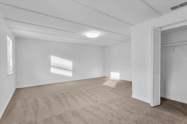 unfurnished bedroom with a closet, carpet floors, and beamed ceiling