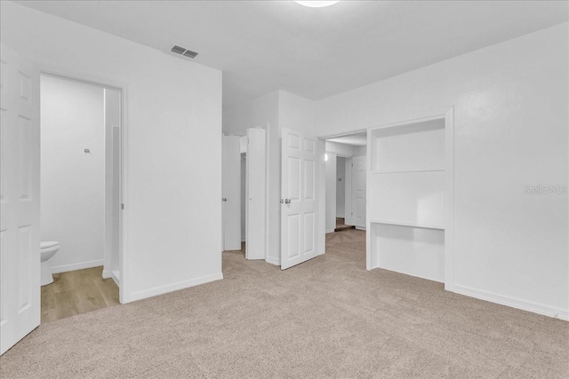 unfurnished bedroom with connected bathroom, a closet, and light carpet