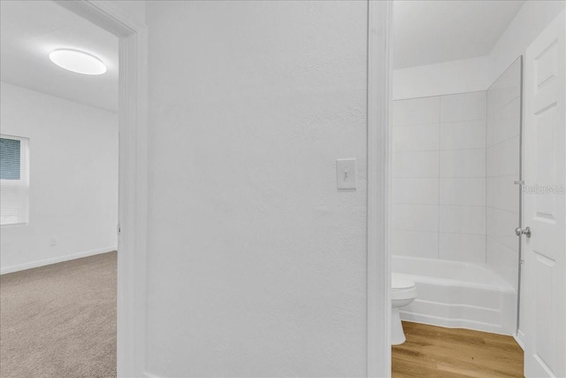 bathroom with toilet, shower / bathtub combination, and hardwood / wood-style flooring