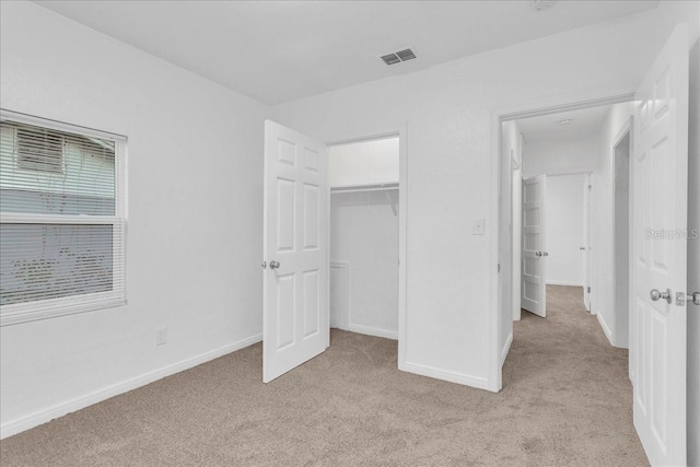 unfurnished bedroom with light colored carpet and a closet