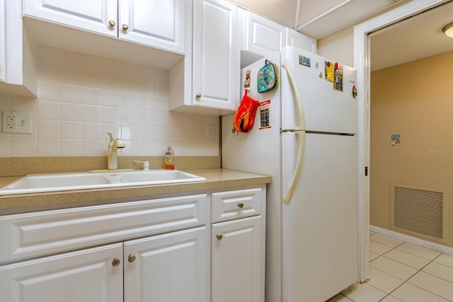 kitchen featuring white cabinets, white refrigerator, tasteful backsplash, and sink