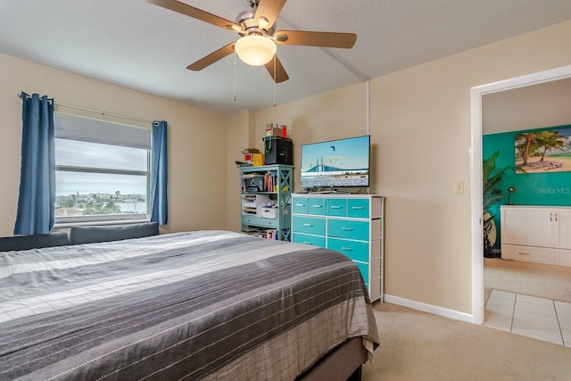 carpeted bedroom featuring ceiling fan and a textured ceiling