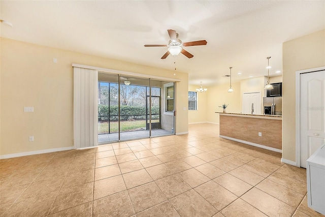 spare room featuring ceiling fan with notable chandelier and light tile patterned floors