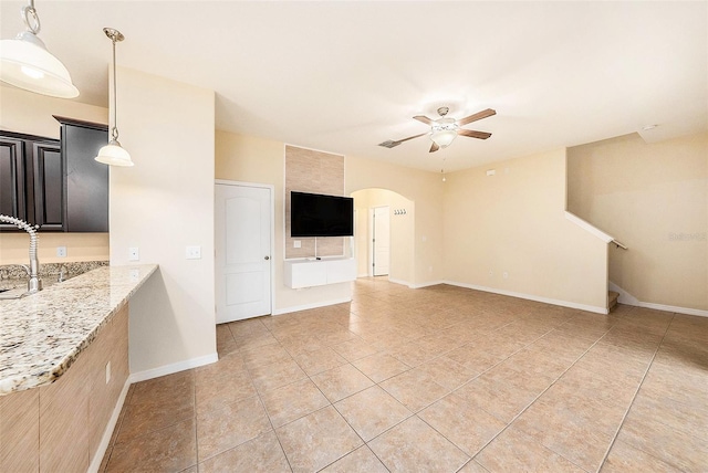 unfurnished living room featuring ceiling fan, sink, and light tile patterned floors