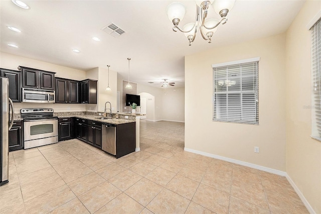 kitchen with light tile patterned flooring, appliances with stainless steel finishes, decorative light fixtures, sink, and light stone counters