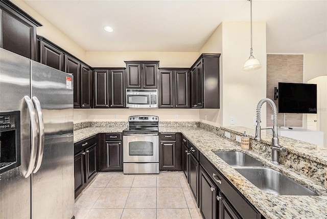 kitchen with appliances with stainless steel finishes, decorative light fixtures, sink, light tile patterned floors, and light stone counters