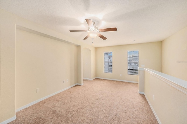 spare room featuring a textured ceiling, light colored carpet, and ceiling fan