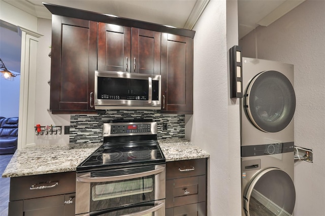 kitchen featuring stainless steel appliances, stacked washer / dryer, backsplash, and light stone counters