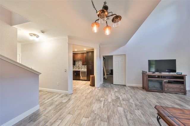 unfurnished living room featuring crown molding, a chandelier, and light hardwood / wood-style floors