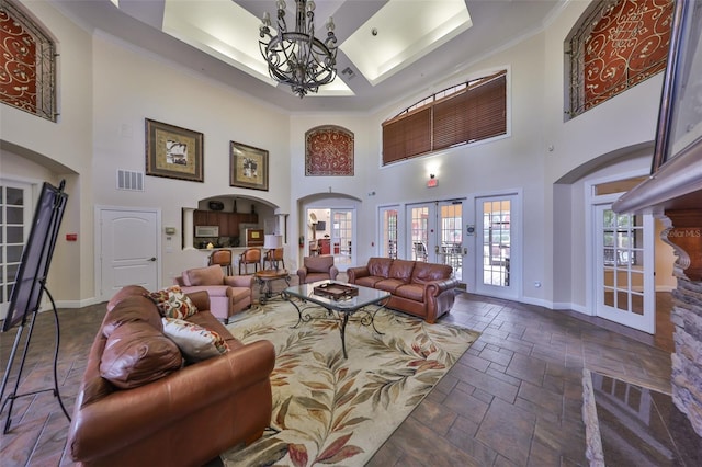 living room featuring french doors, a notable chandelier, crown molding, and a towering ceiling