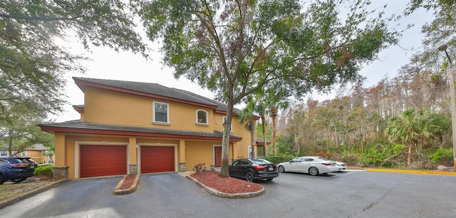2160 Chianti Pl Unit 11-0117, Palm Harbor, FL 34683 - view of side of home featuring stucco siding, aphalt driveway, stone siding, and a garage