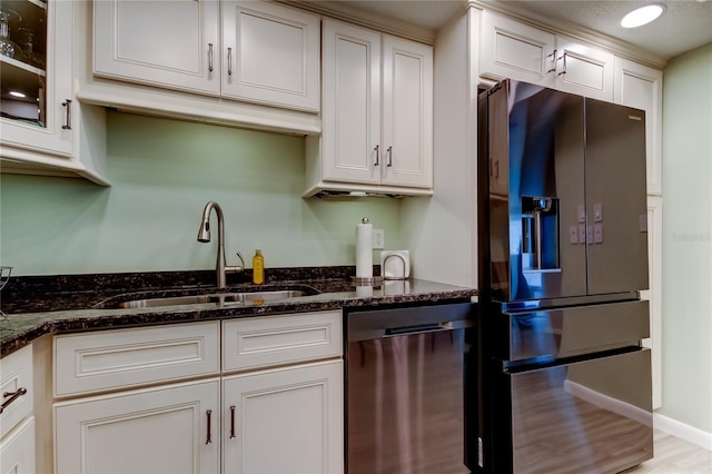 kitchen featuring light hardwood / wood-style flooring, sink, white cabinets, dark stone countertops, and stainless steel appliances