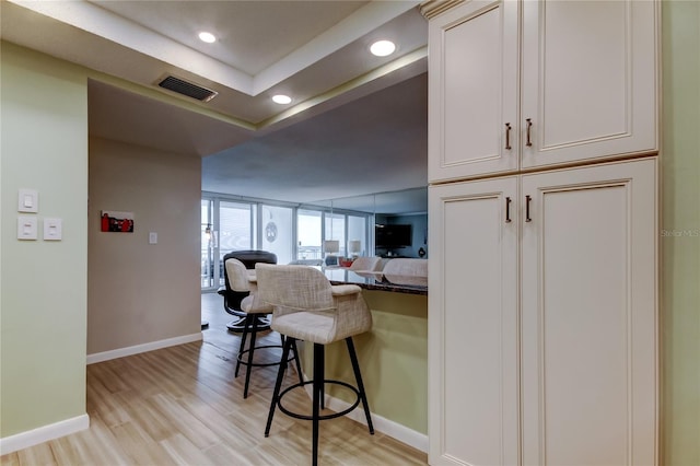 kitchen with light hardwood / wood-style floors, a kitchen breakfast bar, and dark stone countertops