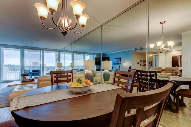 dining space with light hardwood / wood-style floors, crown molding, a chandelier, and a healthy amount of sunlight