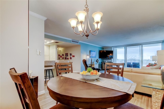 dining room featuring ornamental molding, light hardwood / wood-style floors, and an inviting chandelier