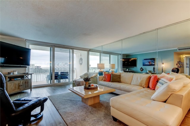 living room featuring hardwood / wood-style flooring, a textured ceiling, a wall of windows, and ornamental molding