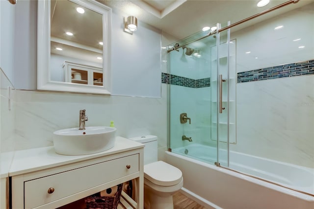 full bathroom with wood-type flooring, bath / shower combo with glass door, toilet, and vanity