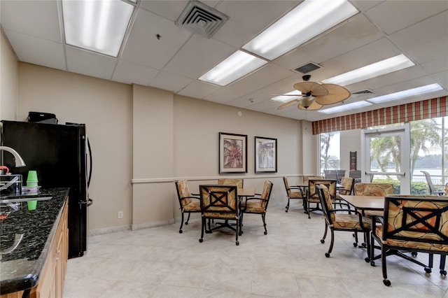 dining space with a drop ceiling and ceiling fan