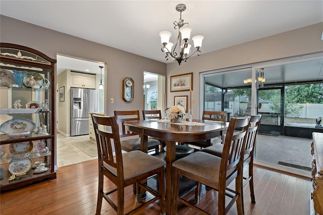 dining space with light hardwood / wood-style floors and a notable chandelier