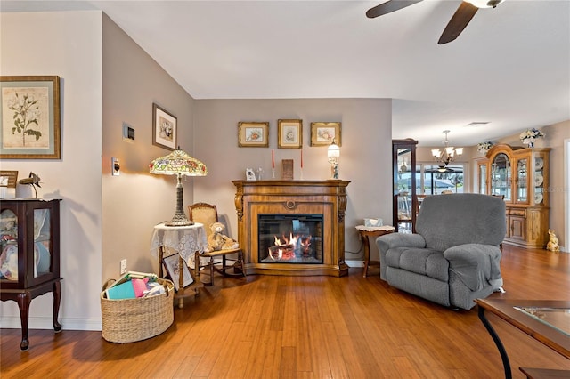 sitting room with ceiling fan with notable chandelier and hardwood / wood-style flooring