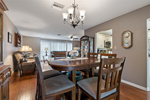 dining room with ceiling fan with notable chandelier and hardwood / wood-style floors