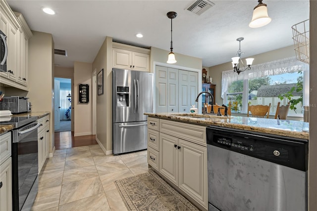 kitchen with decorative light fixtures, sink, appliances with stainless steel finishes, and light stone countertops