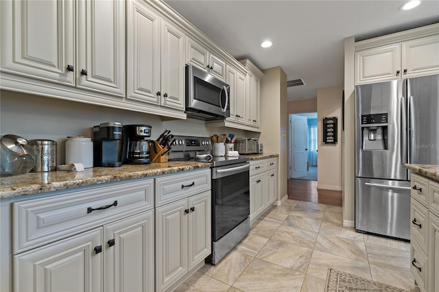 kitchen with appliances with stainless steel finishes, white cabinets, and light stone counters