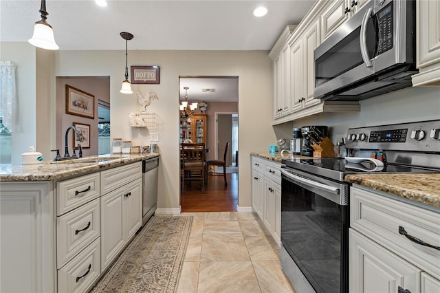 kitchen featuring decorative light fixtures, sink, stainless steel appliances, and white cabinetry