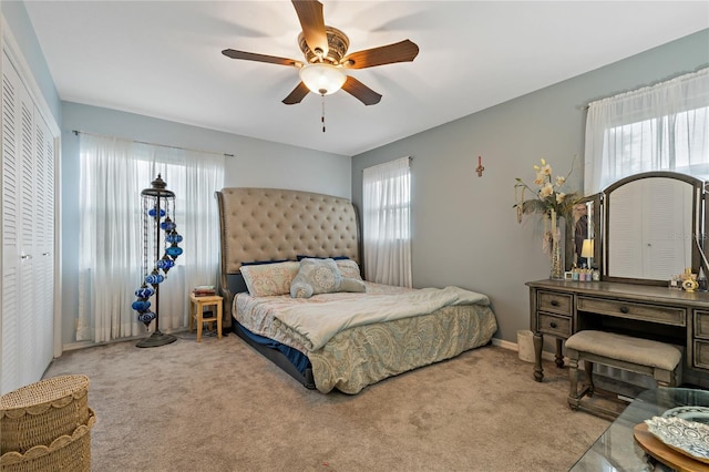 carpeted bedroom with ceiling fan, multiple windows, and a closet