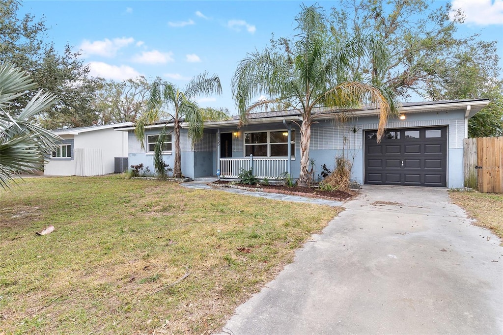 ranch-style house with central AC unit, a garage, a front lawn, and covered porch