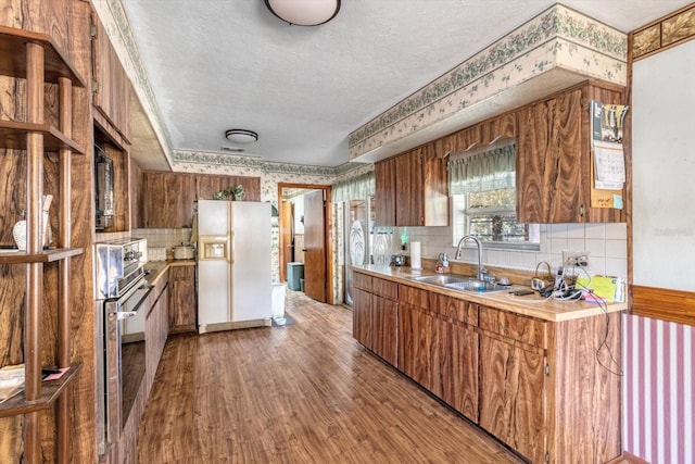 kitchen with backsplash, wood-type flooring, sink, a textured ceiling, and white fridge with ice dispenser