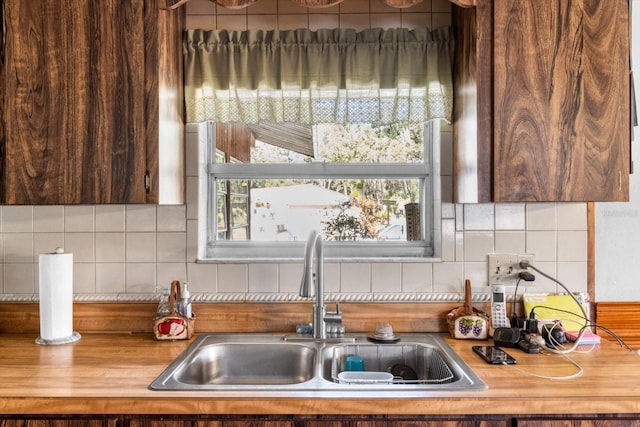 kitchen featuring wood counters, decorative backsplash, and sink