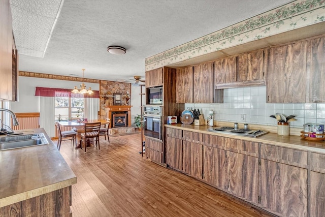 kitchen with stovetop, light hardwood / wood-style floors, sink, wall oven, and stainless steel microwave