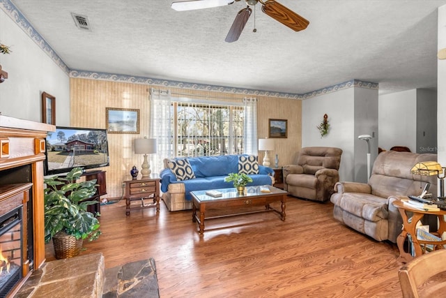 living room with ceiling fan, wood-type flooring, and a textured ceiling