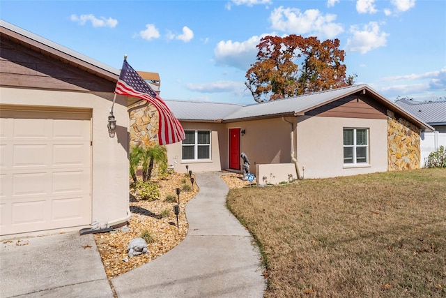 ranch-style house featuring stucco siding, stone siding, an attached garage, a front yard, and metal roof