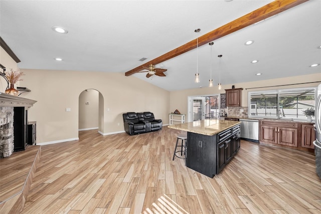 kitchen featuring dishwasher, a ceiling fan, arched walkways, open floor plan, and a breakfast bar area