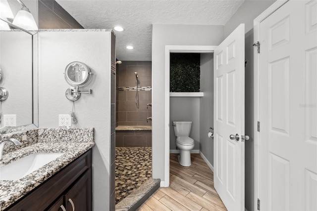 bathroom featuring a shower stall, toilet, vanity, and a textured ceiling