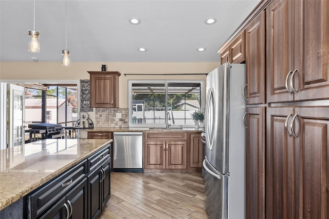 kitchen featuring decorative light fixtures, a wealth of natural light, stainless steel appliances, and a sink