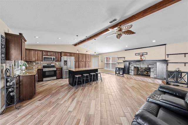 living area featuring light wood-style flooring, visible vents, vaulted ceiling with beams, and ceiling fan