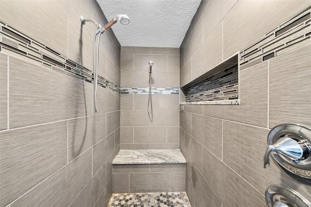 full bathroom featuring a textured ceiling and tiled shower