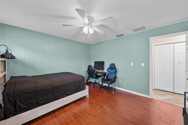 bedroom featuring wood finished floors, visible vents, a ceiling fan, and baseboards