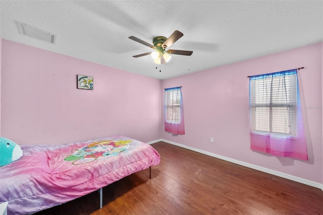 bedroom with visible vents, baseboards, wood finished floors, and a textured ceiling