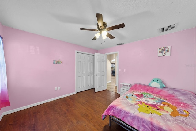 bedroom with a closet, wood finished floors, visible vents, and baseboards