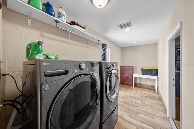 laundry room featuring independent washer and dryer, light wood-style floors, visible vents, and laundry area